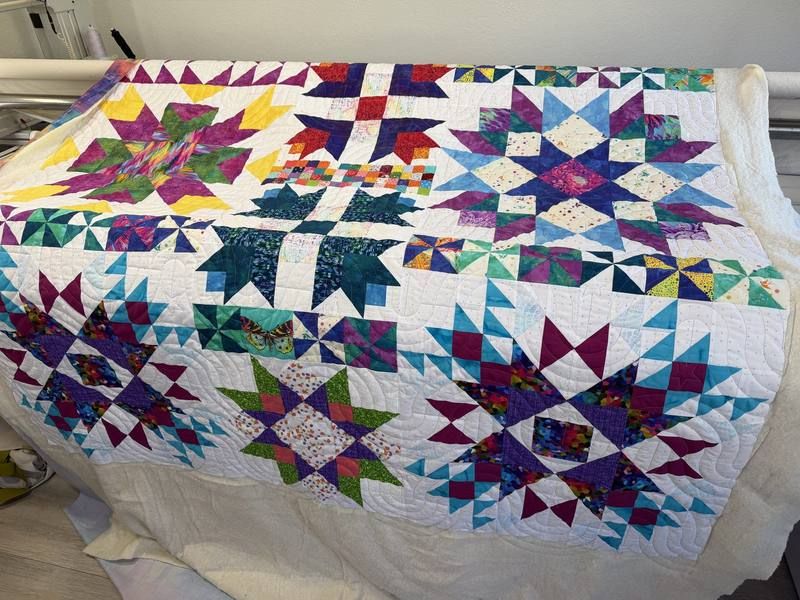 Vibrant jewel-tone star quilt on longarm machine