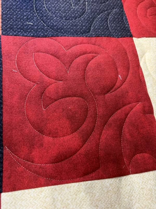 Feathered heart stitching on red quilt