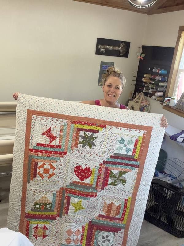 Nichole King holding sampler quilt in her studio